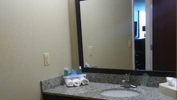 A bathroom with a granite countertop, a sink, a mirror, and a towel rack.