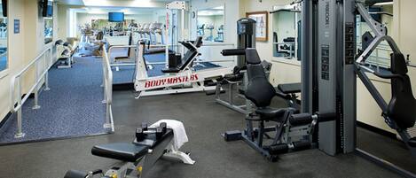 A gym with various exercise equipment, including treadmills, weight machines, and free weights.