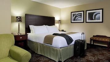 Habitación de hotel con cama, lámparas de noche, una silla, un banco y una maleta.
