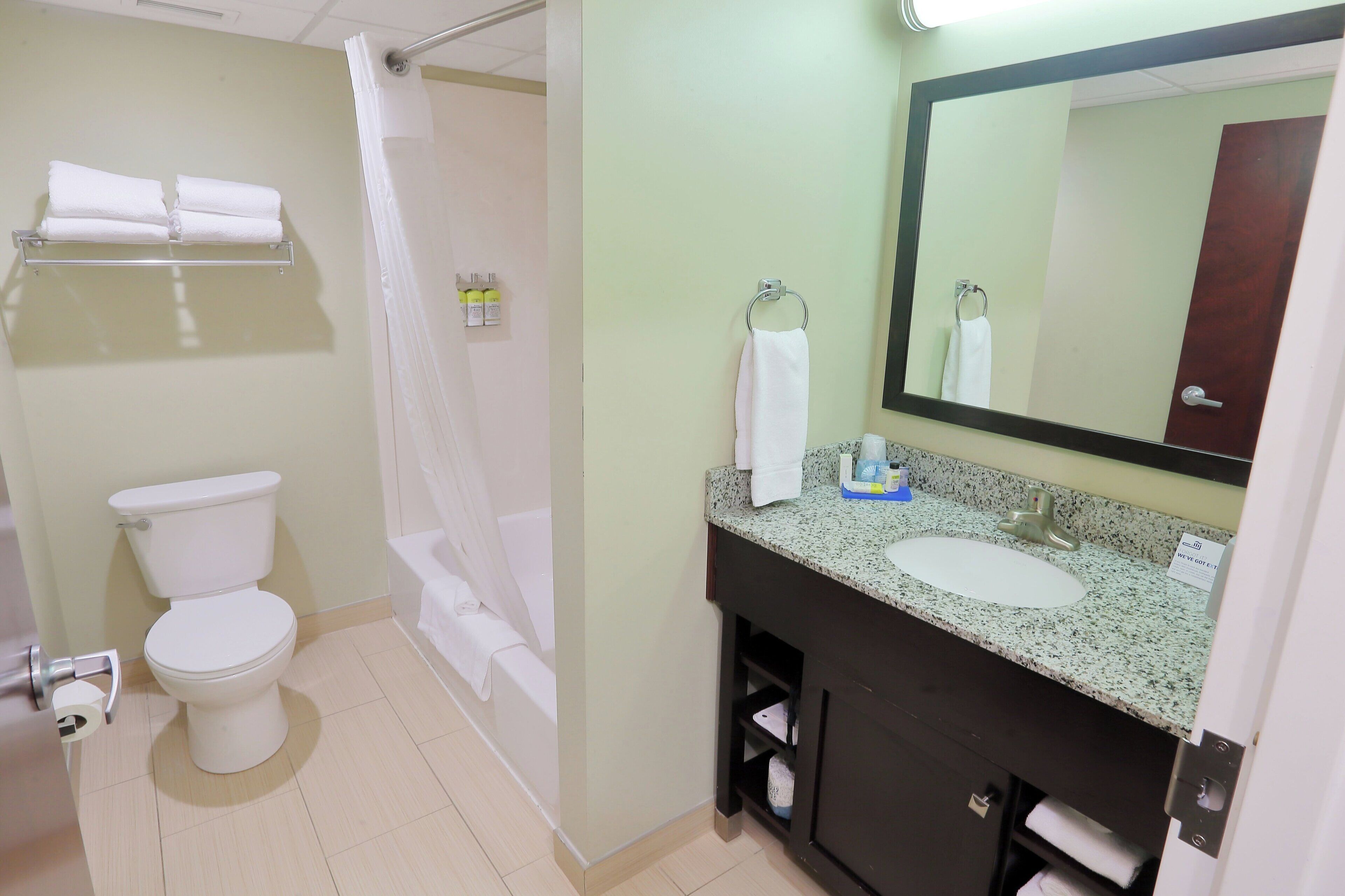 Un baño con inodoro, lavamanos, espejo y cortina de ducha.