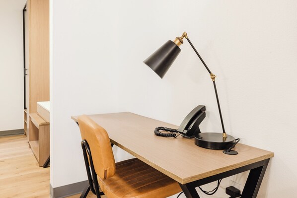 A workspace with a wooden desk, a leather chair, a black desk lamp, and a telephone.