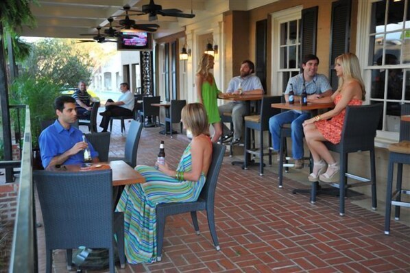 An outdoor patio with brick flooring, wicker chairs, and tables.