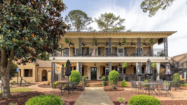 A two-story building with a covered patio area featuring outdoor seating and ceiling fans.