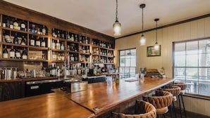 A bar with wooden shelves stocked with bottles, a long counter, and bar stools.