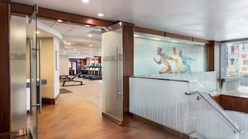 A modern interior with a glass partition, wooden flooring, and a staircase with a glass railing.