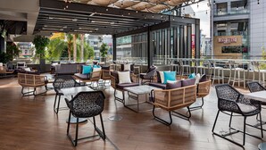 An outdoor seating area with wicker furniture, a glass railing, and a view of the cityscape.