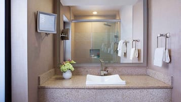 A bathroom with a granite countertop, a white sink, a mirror, and a framed informational display.