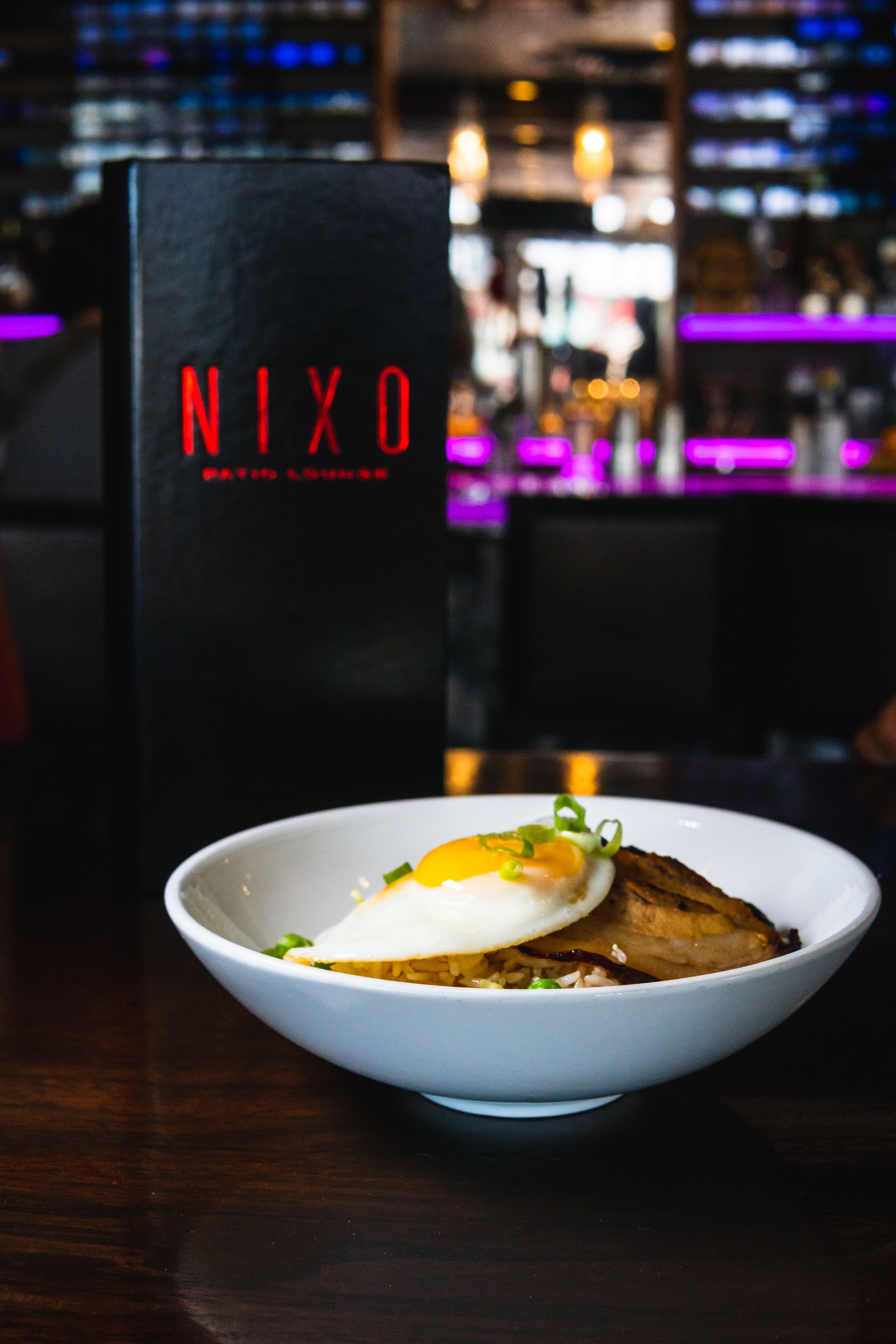 Eine Schüssel Essen mit einem Schild im Hintergrund mit der Aufschrift 'NIXO'.