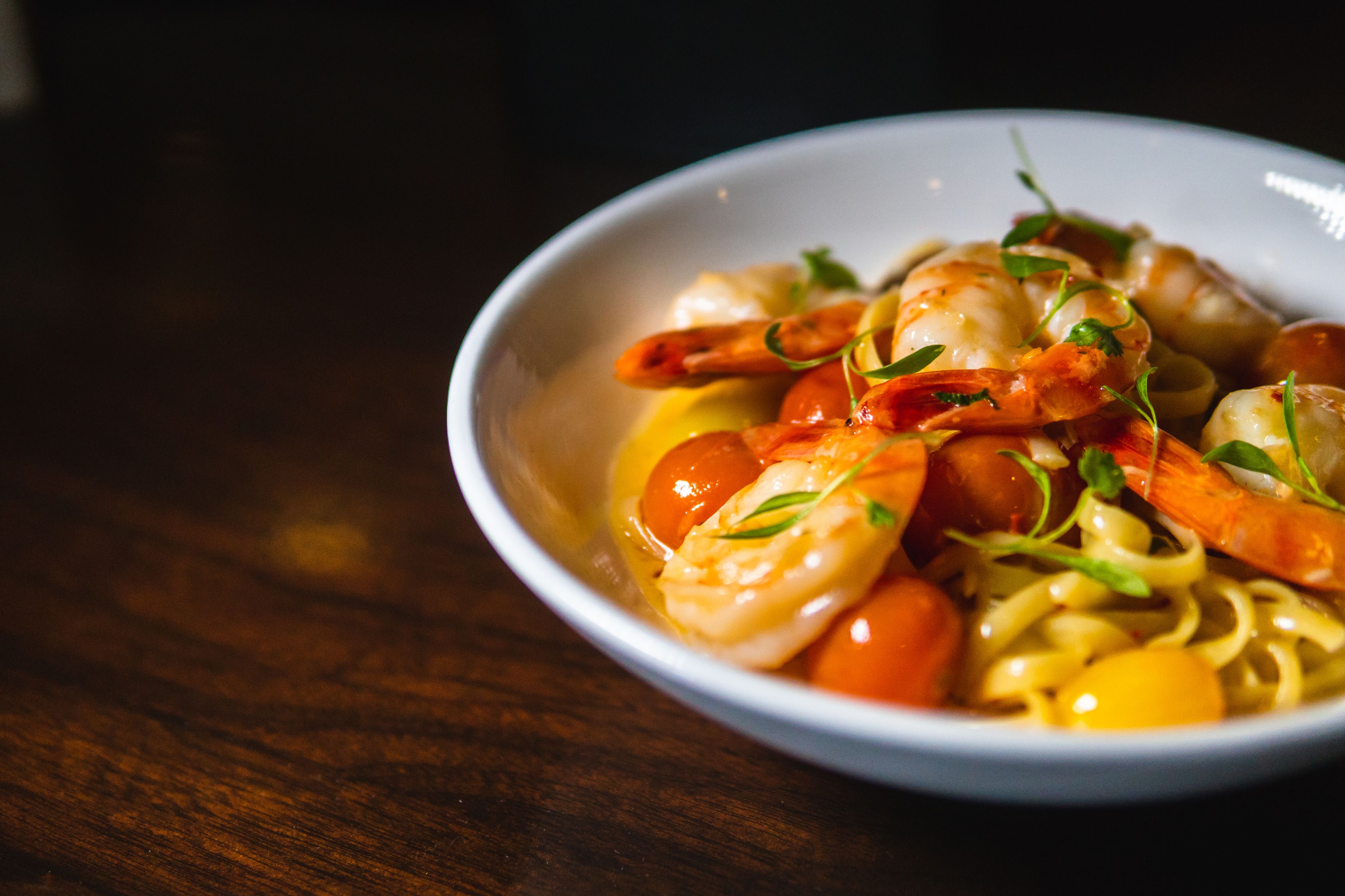Un plato de pasta con camarones y tomates cherry.