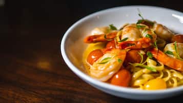 A bowl of pasta with shrimp and cherry tomatoes.