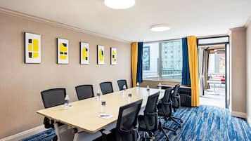 A conference room with a long table, black chairs, and framed artwork on the wall.