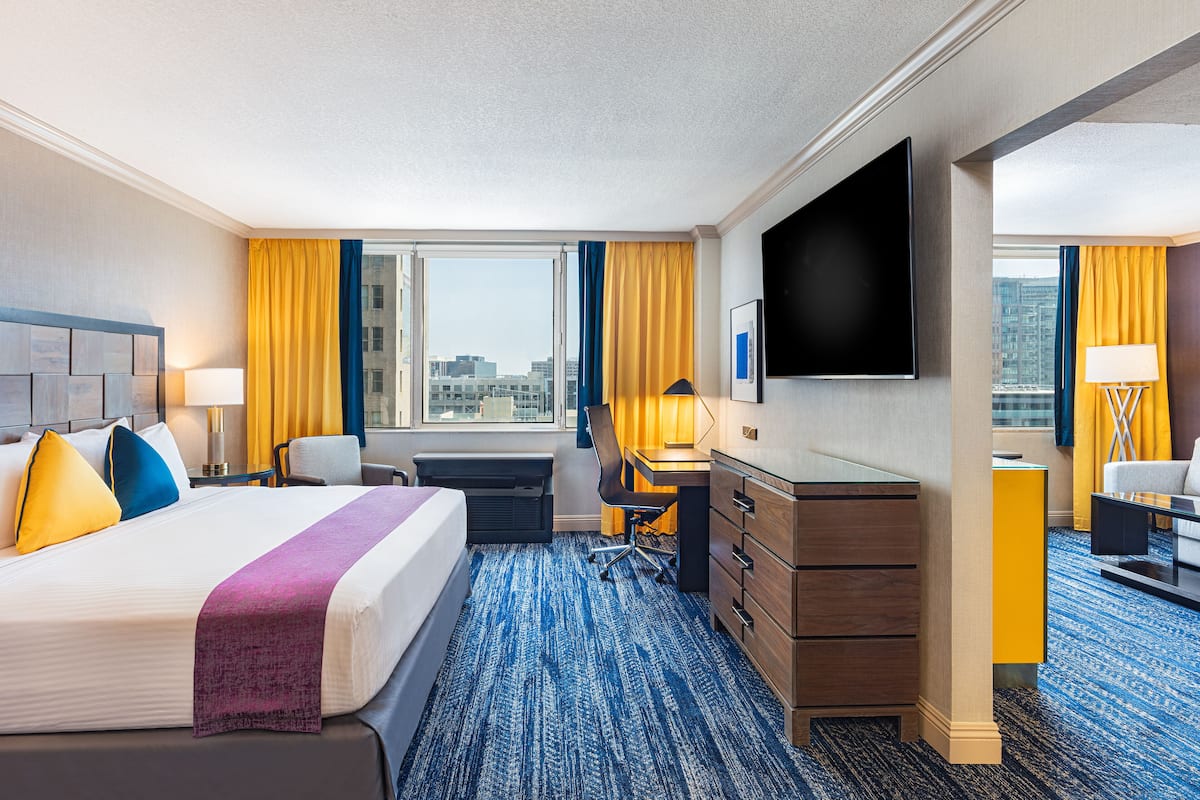 Une chambre d’hôtel avec un grand lit, un bureau, une chaise, une télévision et une vue sur la ville.