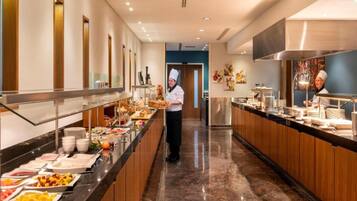 A buffet area with a variety of food items, a chef, and a modern kitchen in the background.