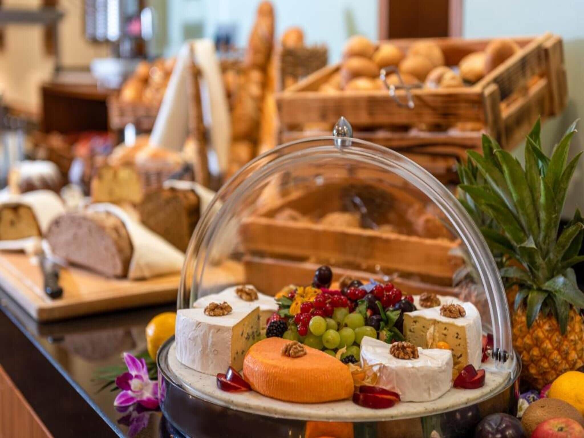 Un bufé con diversos quesos, frutas y pasteles.
