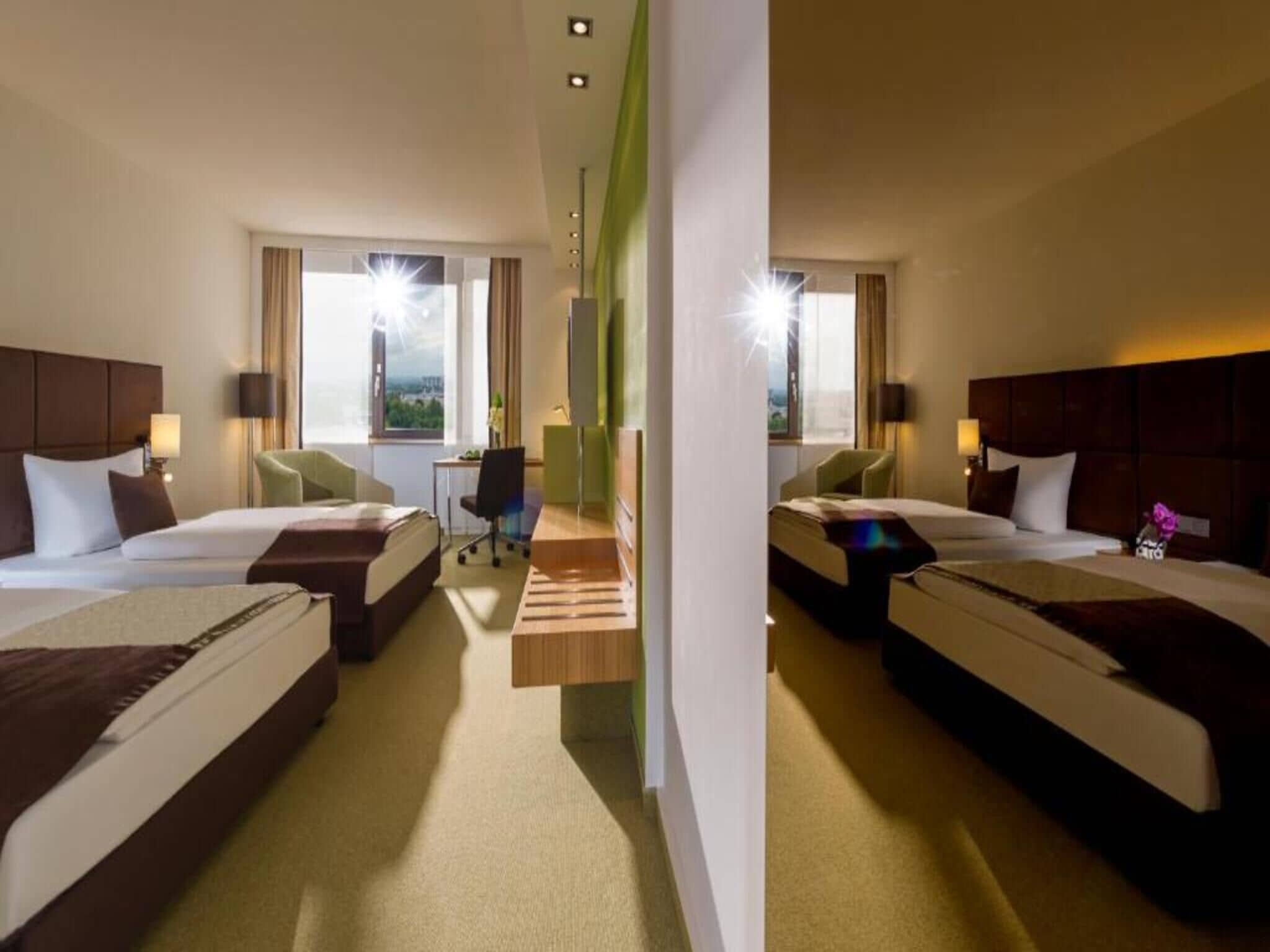 A hotel room with two beds, a desk, and a view of the city.