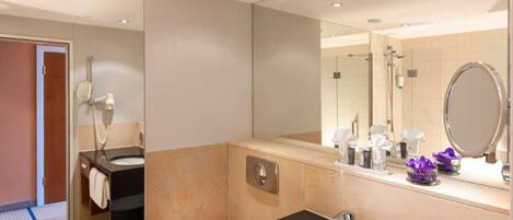 A modern bathroom with a large mirror, a sink, a toilet, and a shower area.