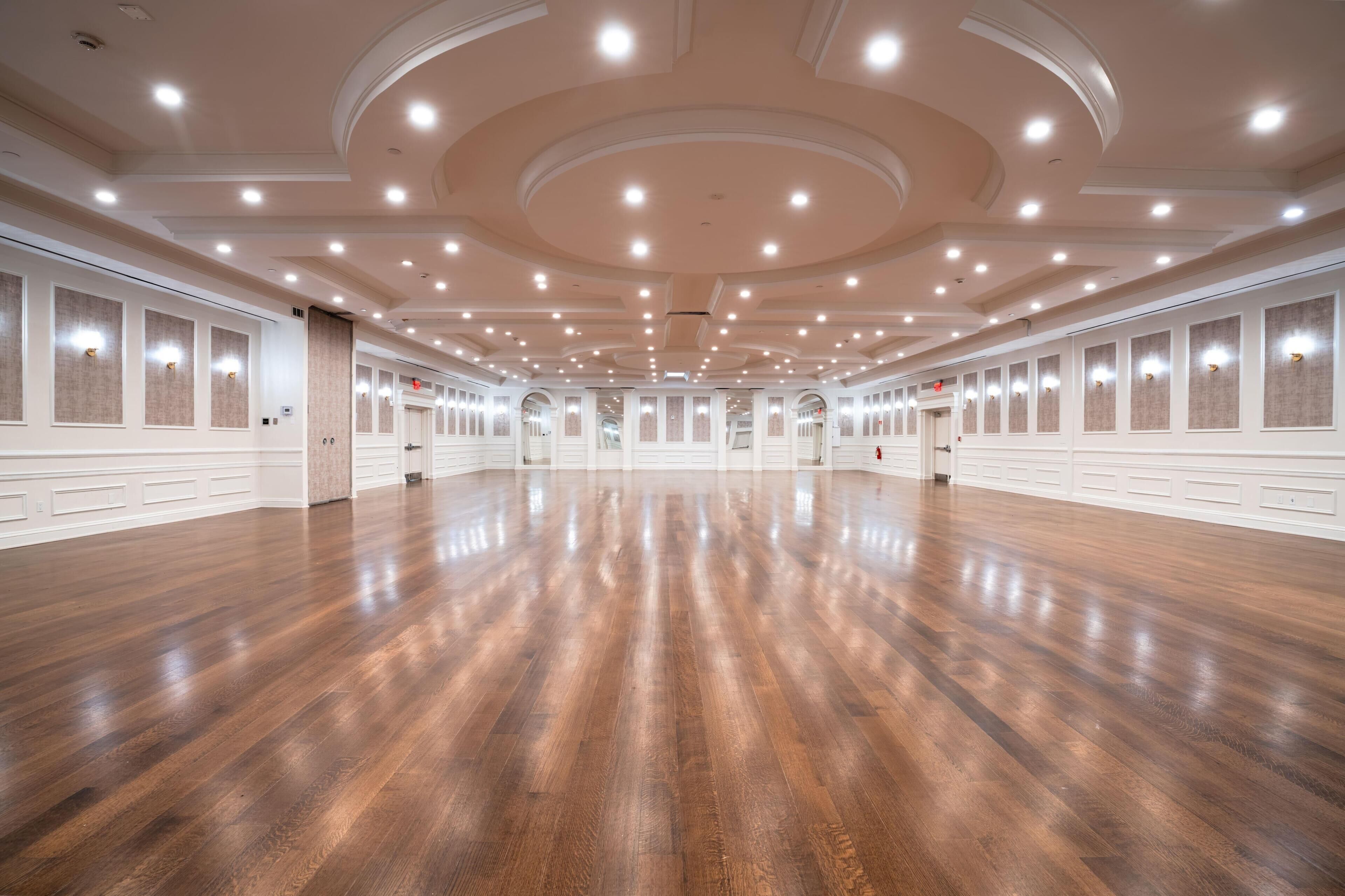 Un vaste hall doté d’un plancher en bois poli et d’un plafond haut avec des luminaires encastrés.
