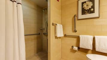 A bathroom with a shower, toilet, and a framed picture on the wall.