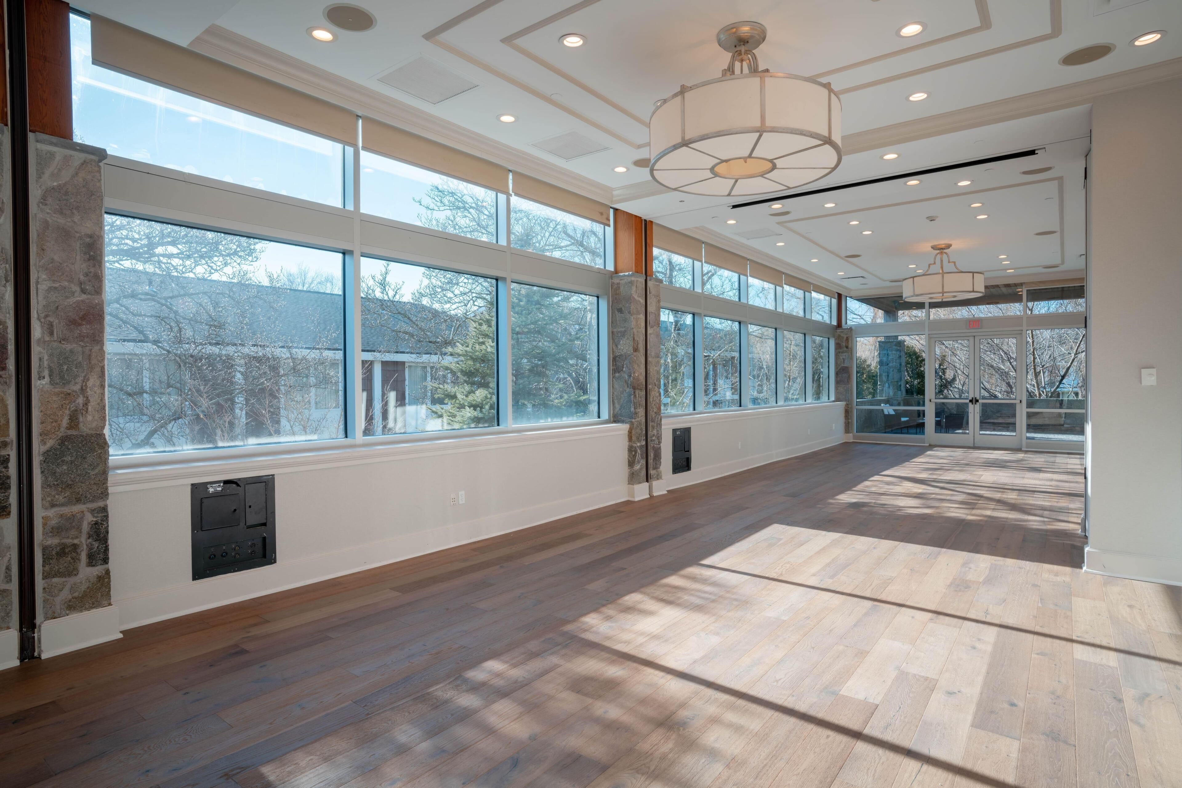A spacious room with large windows, a stone accent wall, and a wooden floor.