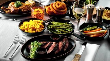 Ein Tisch ist reichhaltig mit verschiedenen Speisen gedeckt, darunter Steak, Spargel und Reis.