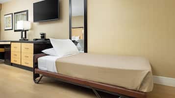 A hotel room with a bed, a desk with a lamp, a flat-screen TV, and a mirror.