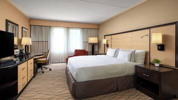 Une chambre d’hôtel avec un grand lit, un bureau avec une chaise, une télévision et deux lampes.
