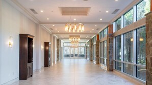 A spacious corridor with stone walls, large windows, and a central chandelier. - Sleepy Hollow Hotel, a Dolce by Wyndham (Tarrytown)
