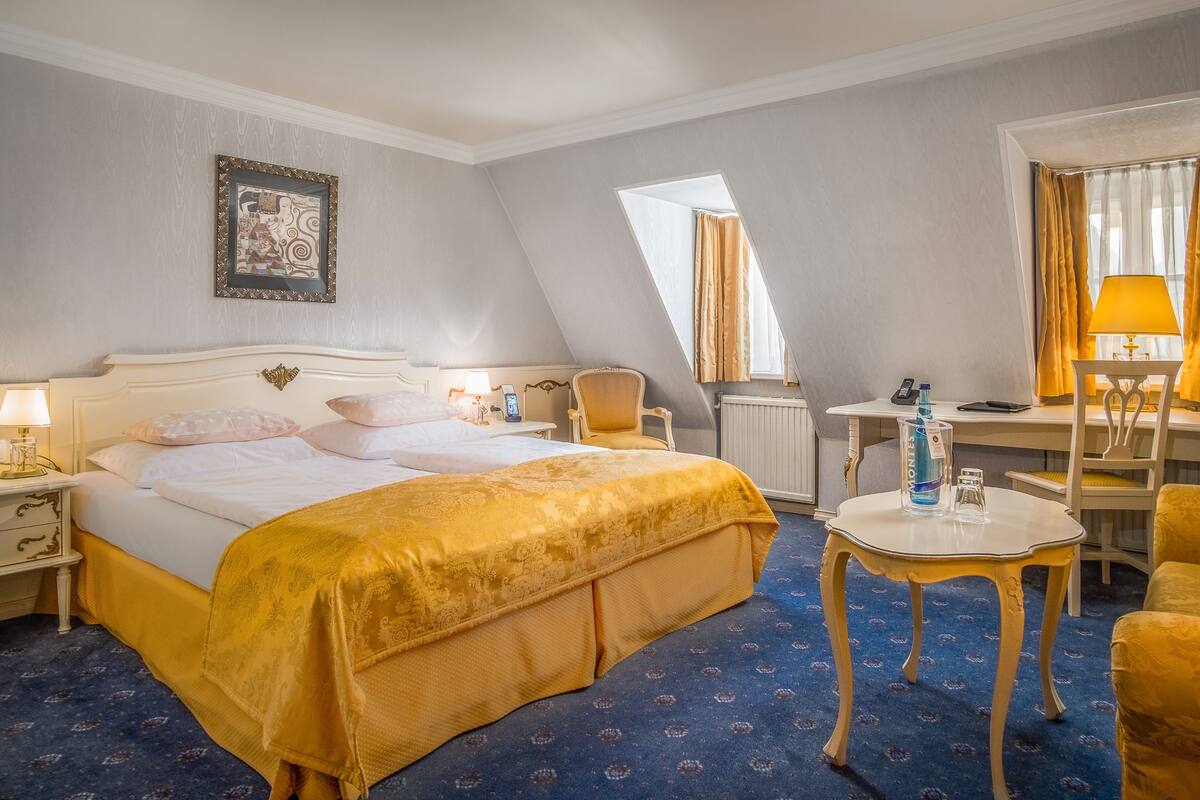 Habitación de hotel con una cama grande, un escritorio, una silla y una mesita.