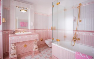 A bathroom with a vanity, sink, mirror, toilet, and a glass-enclosed shower area.