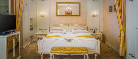 A luxurious bedroom with a large bed, a bench, a television, and a mirror.
