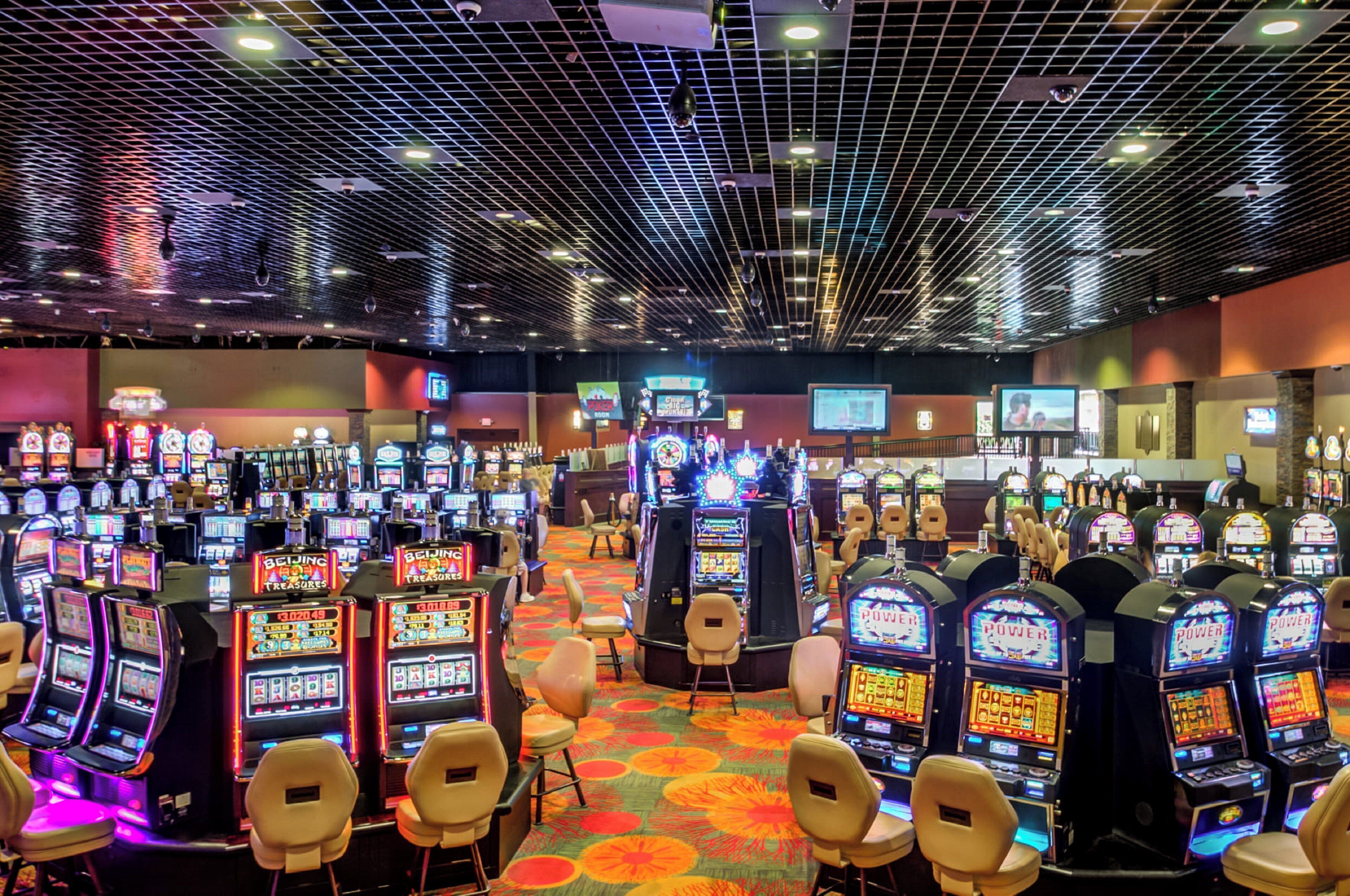 A casino with multiple slot machines and a few chairs.
