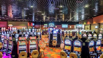 A casino with multiple slot machines and a few chairs.