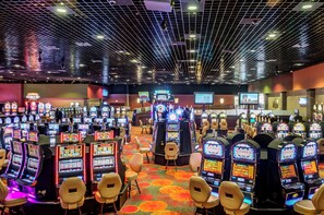 A casino with multiple slot machines and a few chairs. - Holiday Inn Weirton - Steubenville Area by IHG (Weirton)