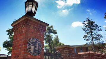 A brick entrance with a sign for West Liberty University, a lamp post, and a clear blue sky.
