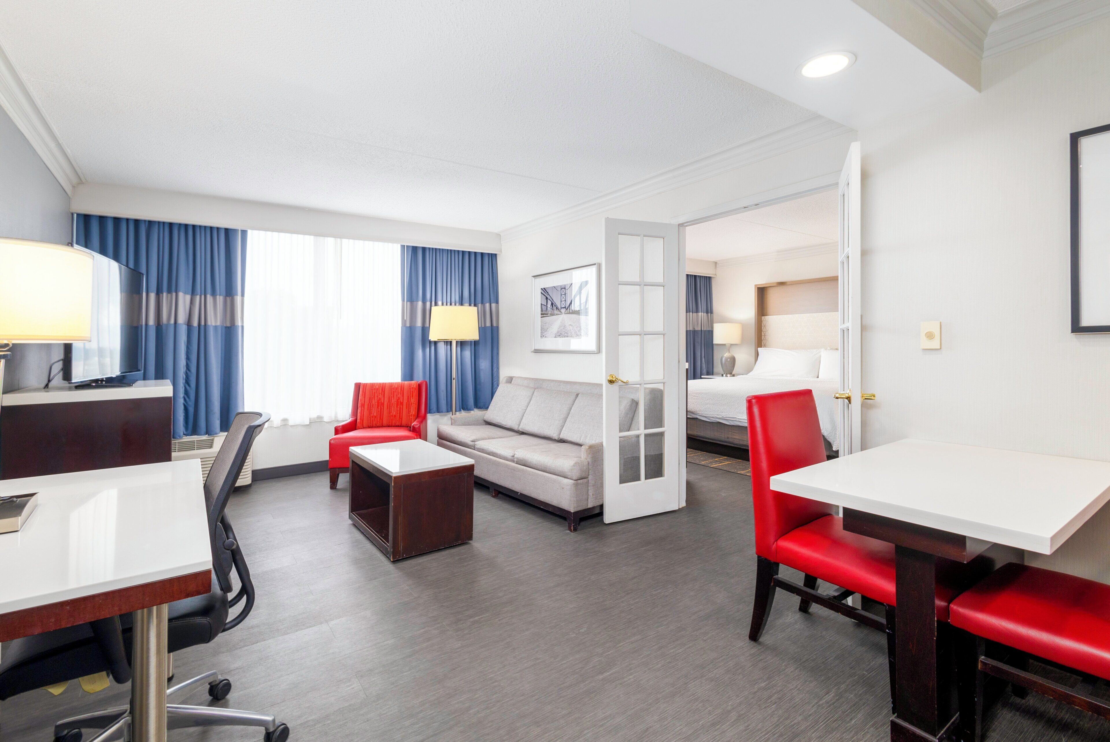 Una habitación de hotel con escritorio, dos sillas, sofá, mesa de centro y cama.