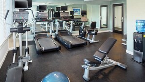 Une salle de sport équipée de tapis de course, d’appareils de musculation et de ballons d’exercice.