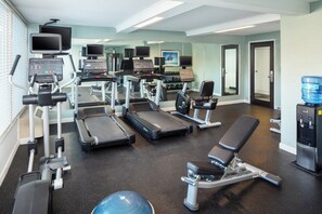 Une salle de sport équipée de tapis de course, d’appareils de musculation et de ballons d’exercice.