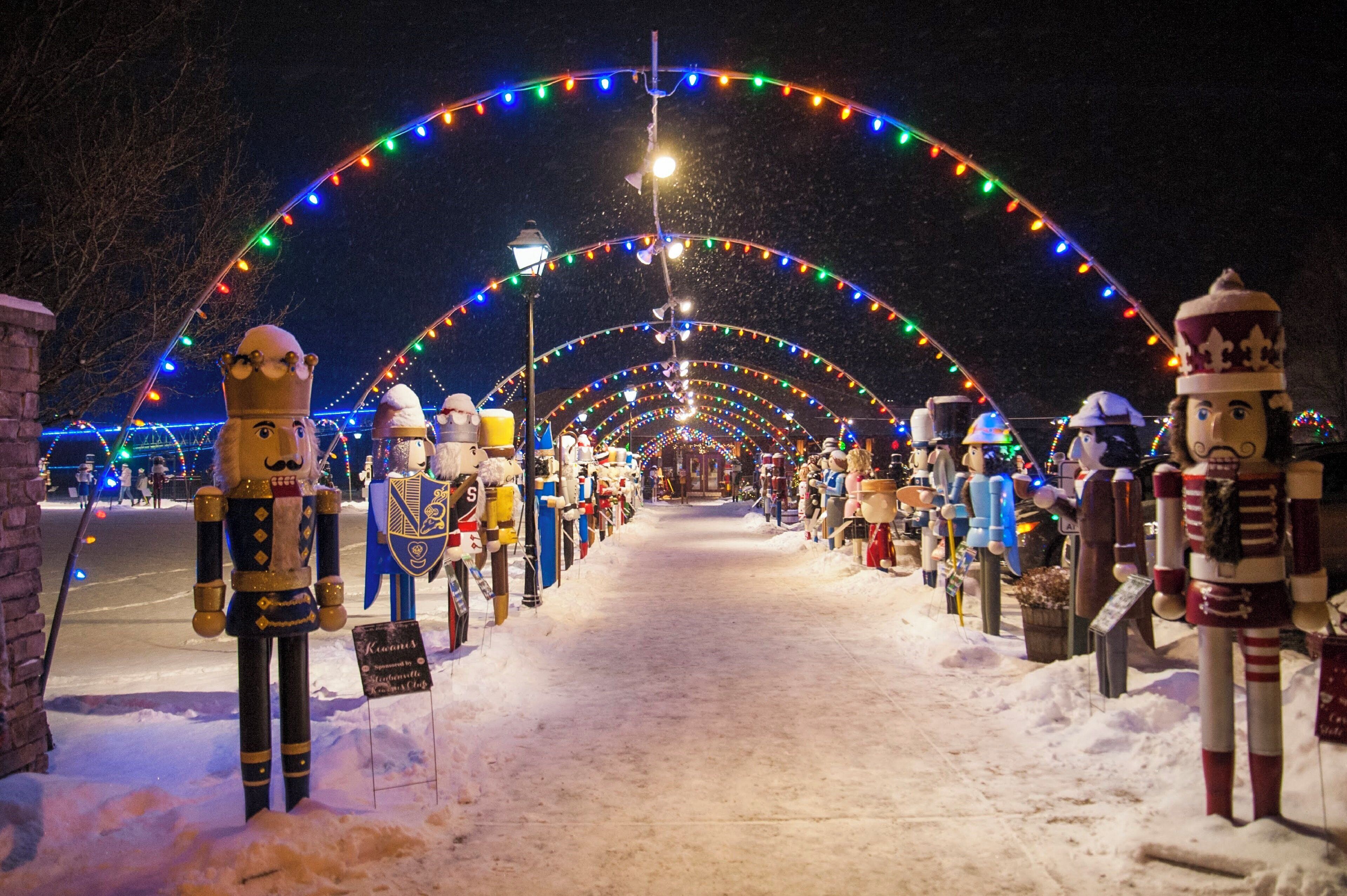 A snow-covered pathway lined with nutcracker statues and colorful lights.