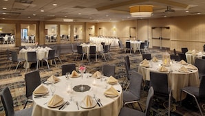 A banquet hall with round tables set for dining, equipped with chairs, tablecloths, and centerpieces. - Holiday Inn Weirton - Steubenville Area by IHG (Weirton)