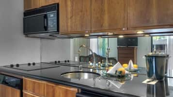 Une cuisine moderne avec des meubles en bois, une cuisinière noire, un évier et un four à micro-ondes.