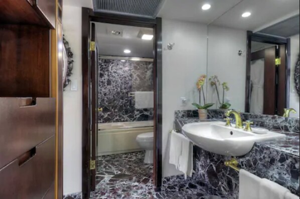 A modern bathroom with a marble floor, a large sink, and a bathtub.