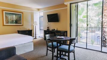 A hotel room with a bed, a desk, a chair, a television, and a view of the outdoors.