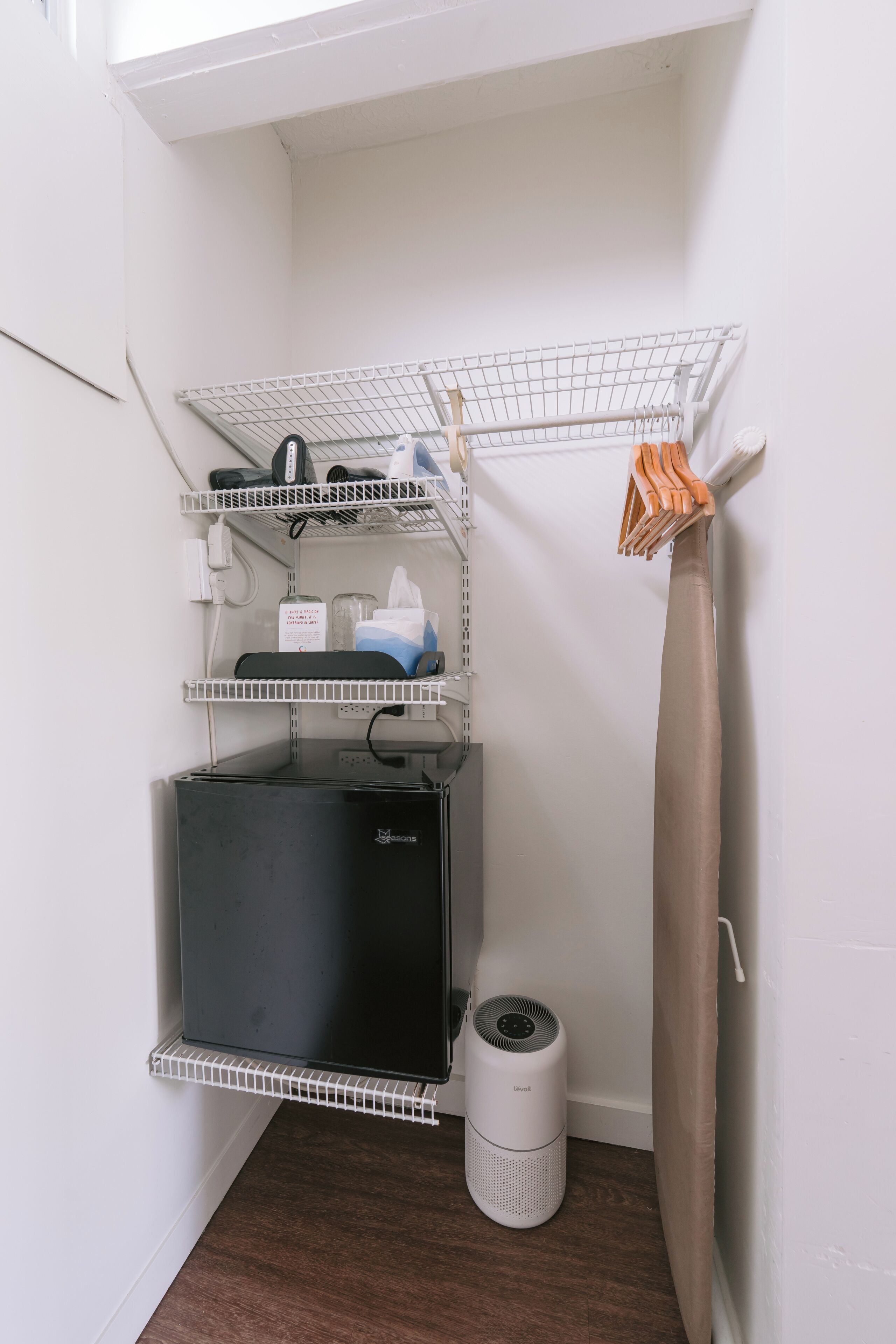 Un espace de rangement compact comprenant des étagères, un aspirateur et un étendoir.