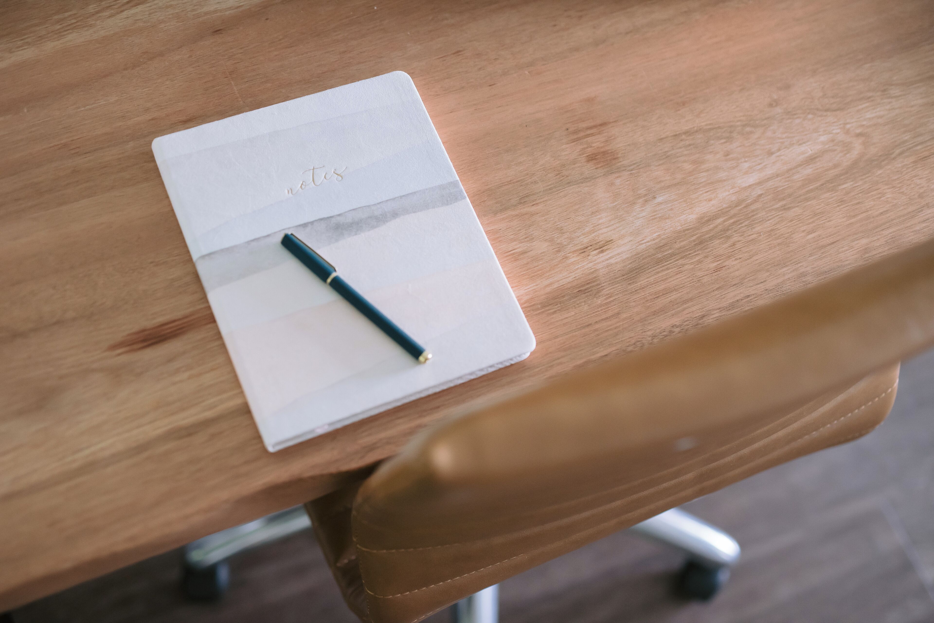 Une table en bois sur laquelle se trouvent un bloc-notes blanc et un stylo.
