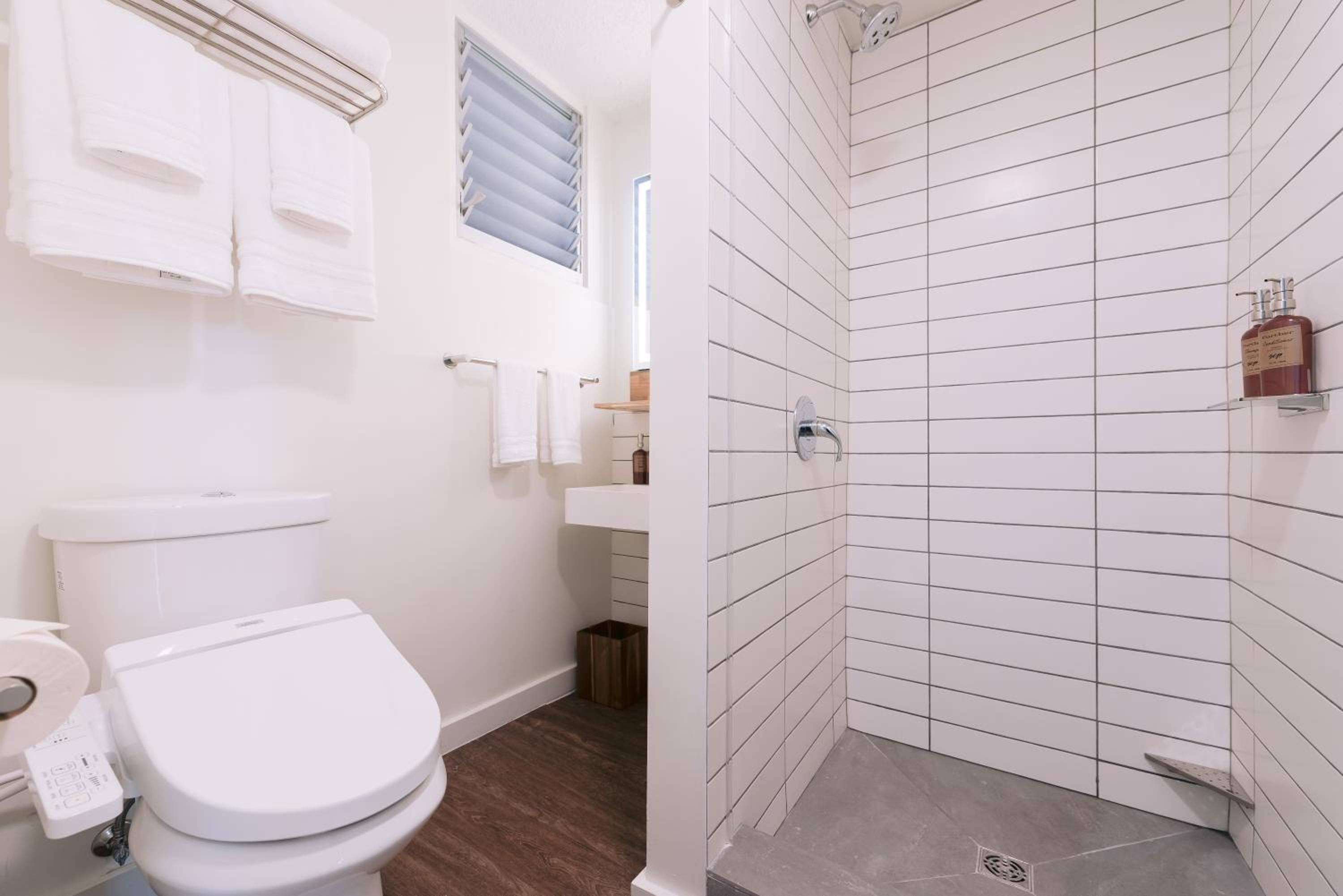 A modern bathroom with a toilet, sink, and shower.