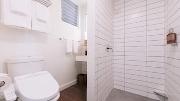Un baño moderno con inodoro, lavamanos y ducha.