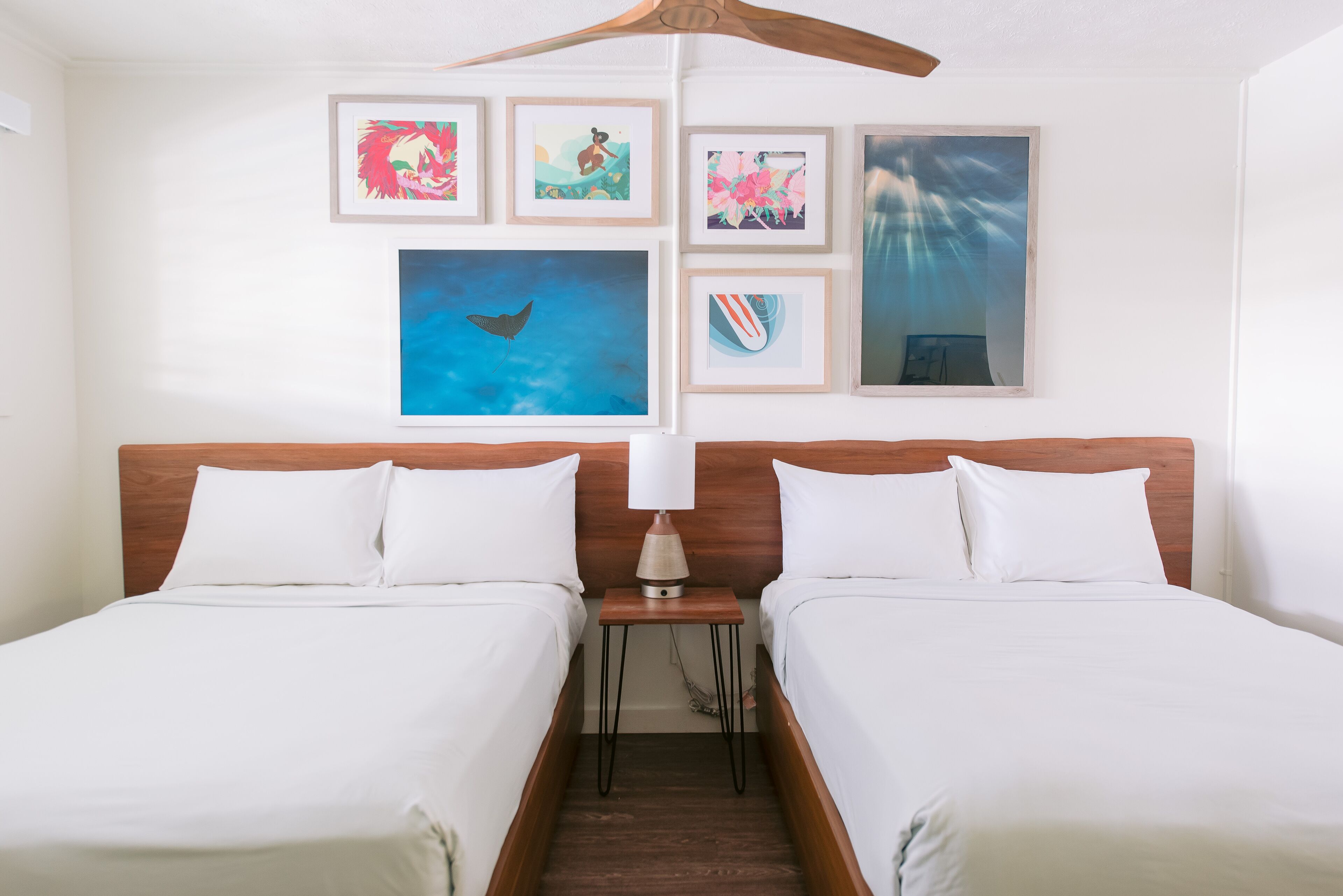 Ein Hotelzimmer mit zwei Betten, einem hölzernen Kopfteil, einem Nachttisch mit Lampe und einem Bild an der Wand.