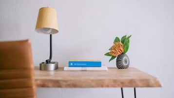 Una mesa de madera con una lámpara, un libro titulado “WELL-BEING PLAYBOOK” y un jarrón decorativo con forma de piña y hojas verdes.