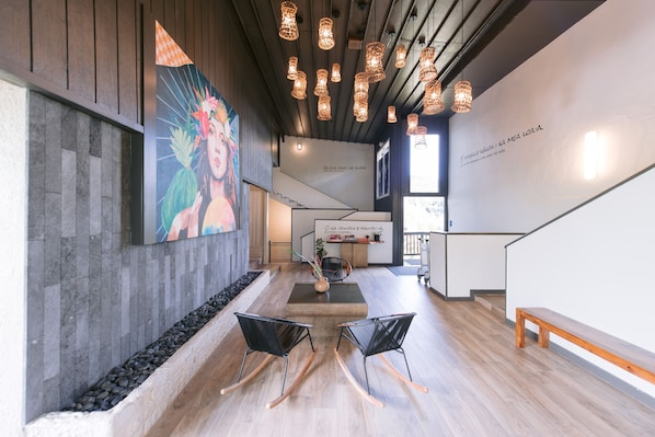 A modern interior with a wooden floor, black rocking chairs, a staircase, and a mural on the wall.