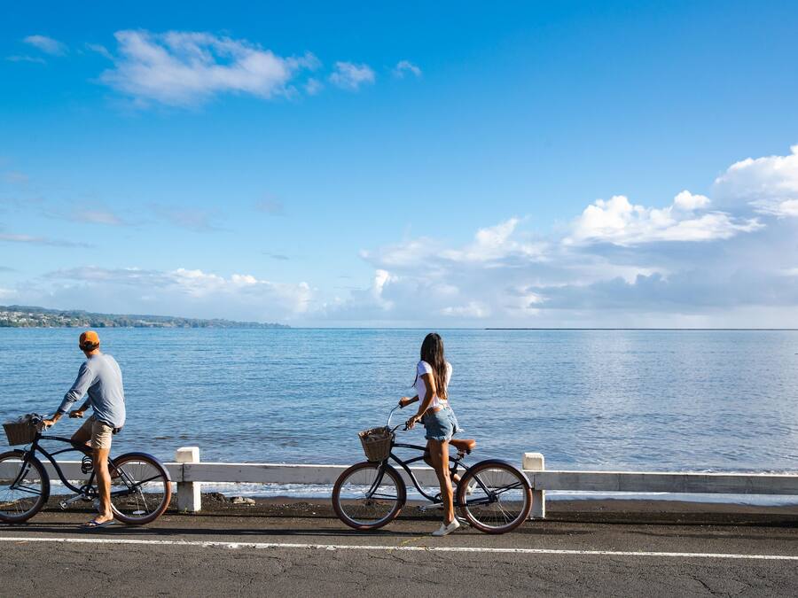 Two people on bicycles by a waterfront with a clear sky.